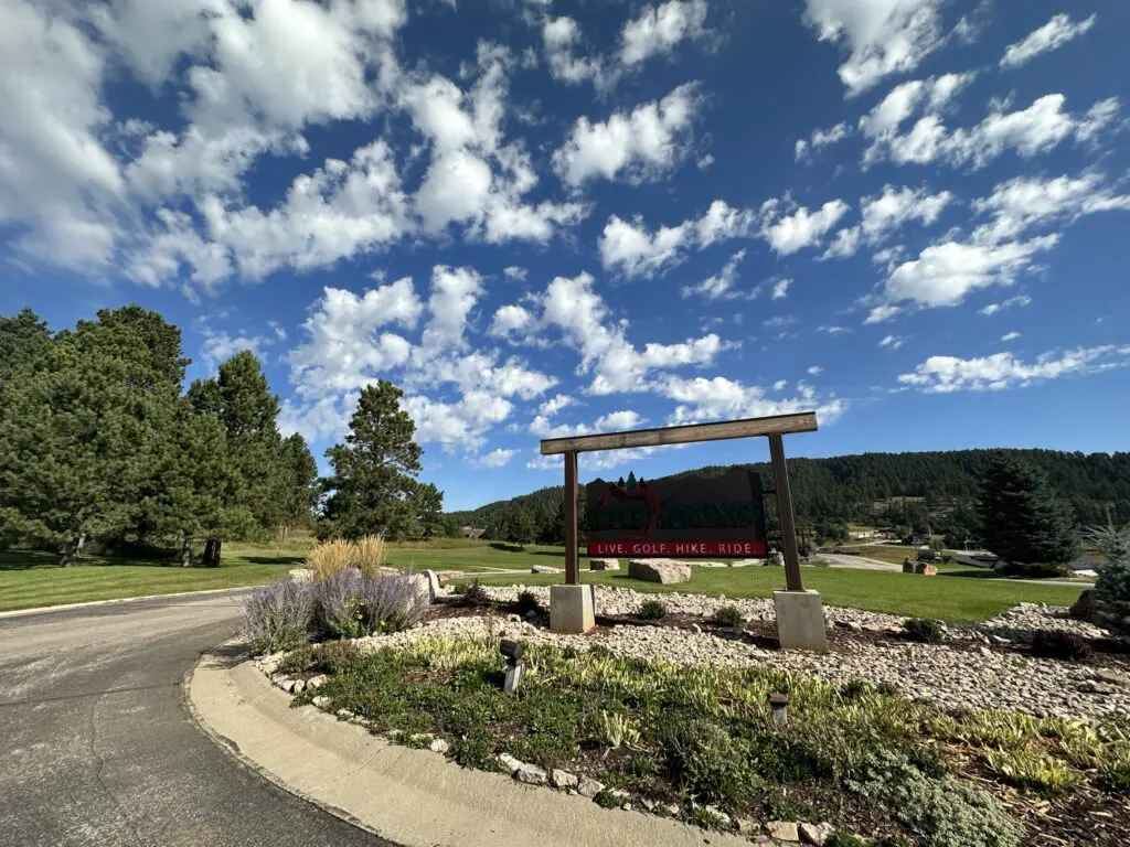 Wooden neighborhood entryway sign that says "Live. Golf. Hike. Ride"